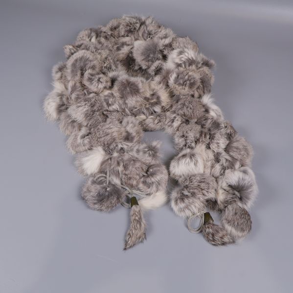 Grå pälssjal i bollformad design på grått underlag