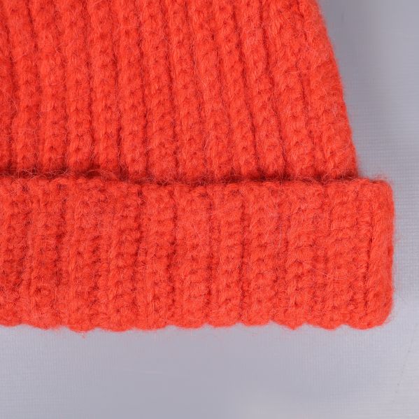 Närbild på ribbad orange stickad mössa och vikning