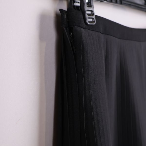 Närbild av sidosöm och plissering i svart tyg