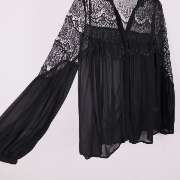 Närbild på ärm och spetsdetaljer på svart blus
