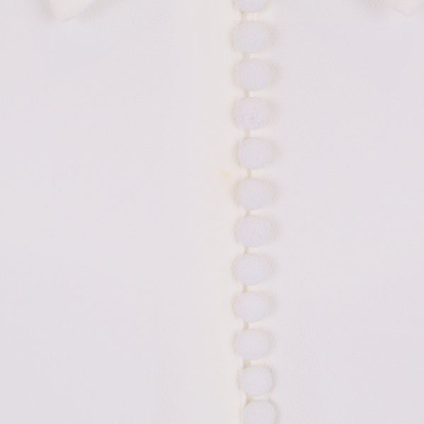 Närbild av mitt fram på blusen och klädda knappar