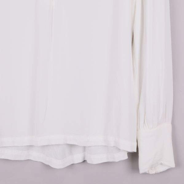 Närbild på nederkant och ärmslut på vit blus