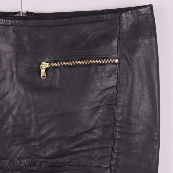 Detalj på guldig dragkedja på svart läderkjol