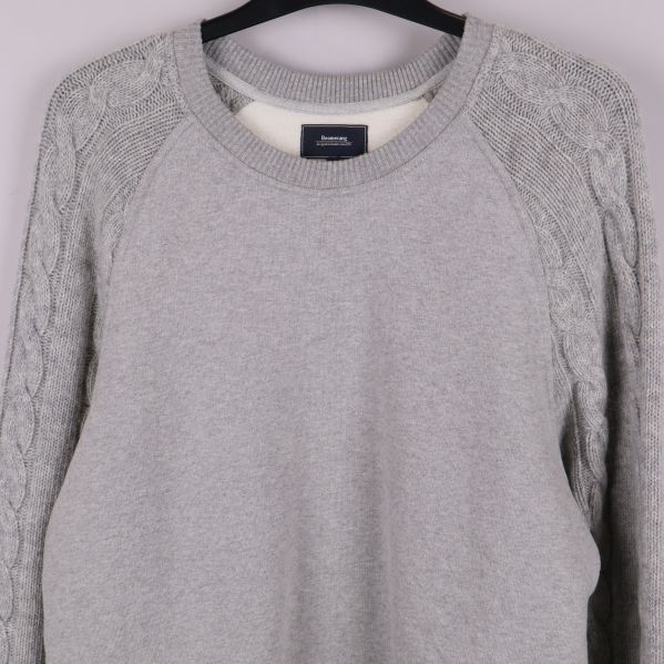 Närbild på tröjans övre fram och stickade ärmar