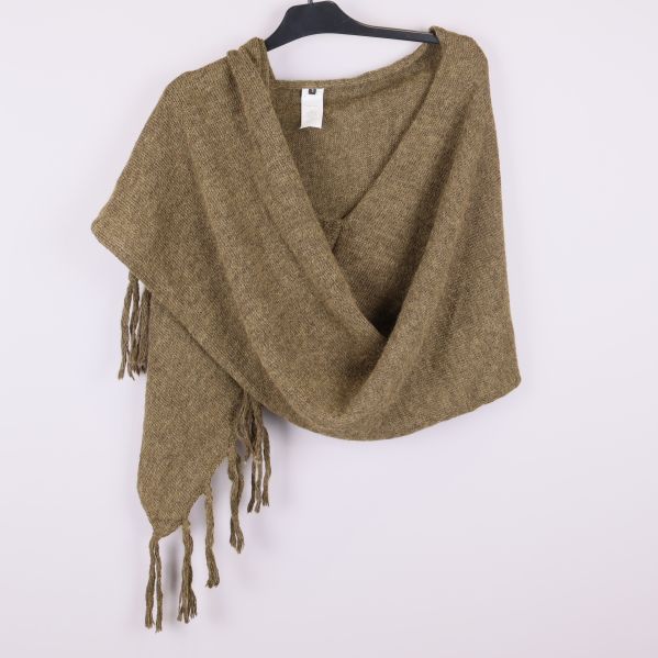 Poncho i stickat material draperad över galge framifrån