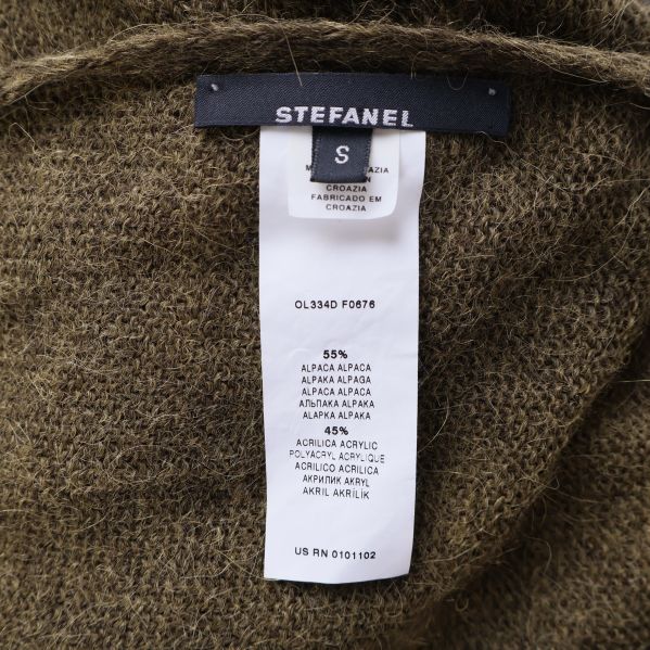 Närbild av tvättrådslapp för brun stickad poncho