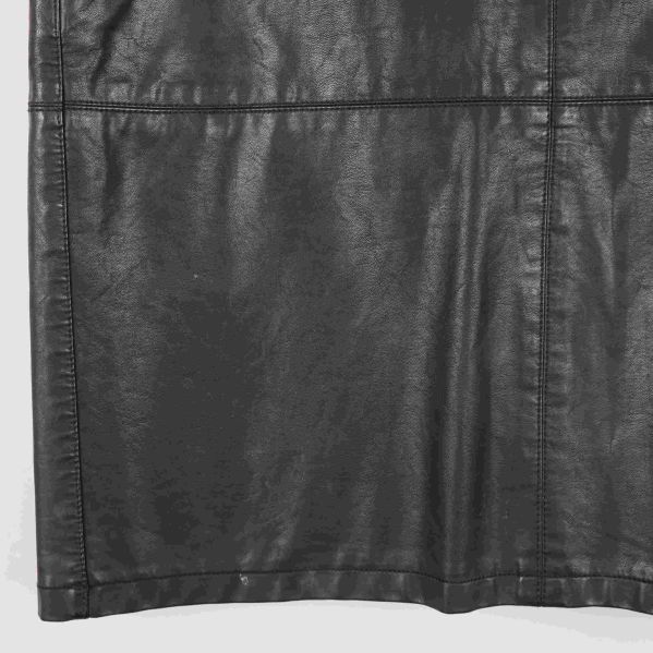 Nedre del av svart kjol i konstläder med synliga sömmar