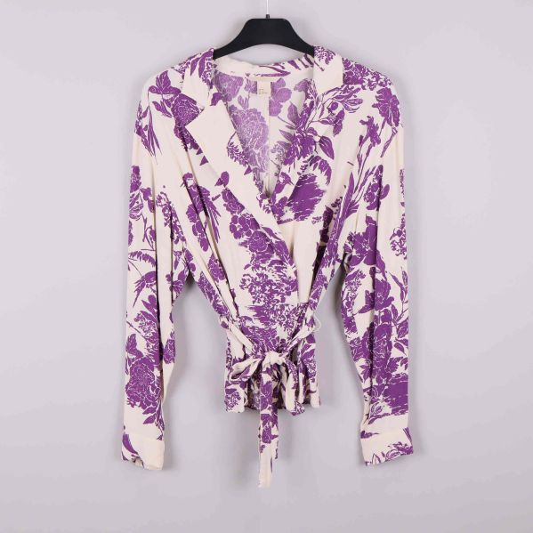 Framsidan av blommig omlottblus med knytband och lila mönster