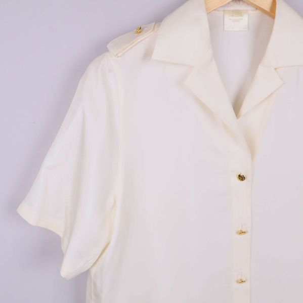 Närbild på krage och axelklaff med knapp på vit skjorta