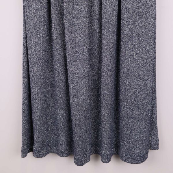 Närbild på nederkanten av grå veckad kjol