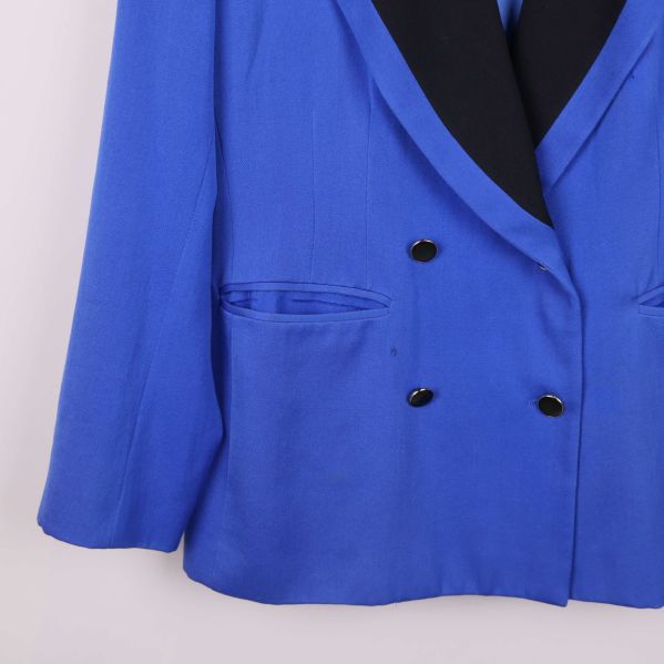 Närbild av vänster ficka och knappar på blå kavajen