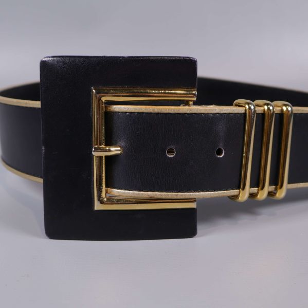 Närbild på spänne med gulddetaljer på svart bälte