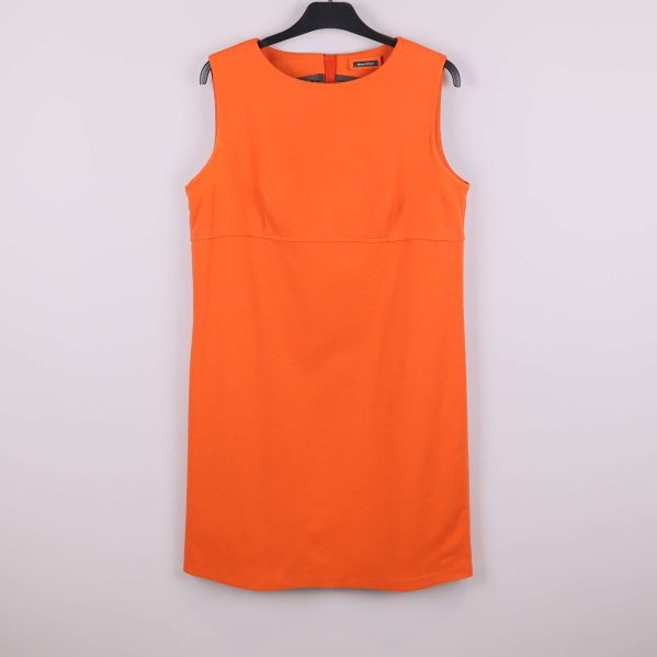 Ärmlös orange klänning hängande på galge, sedd framifrån