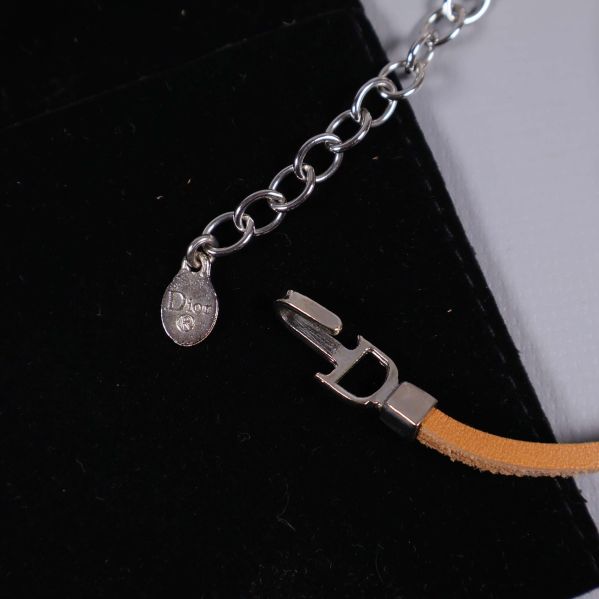 Närbild på spänne och kedja med Dior-logotyp