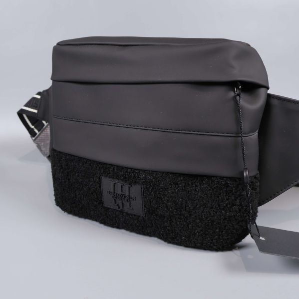 Närbild på svart väska med teddy-detalj framtill