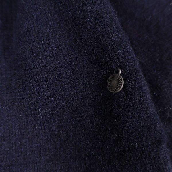 Närbild på metallbricka på mörkblått trikåtyg