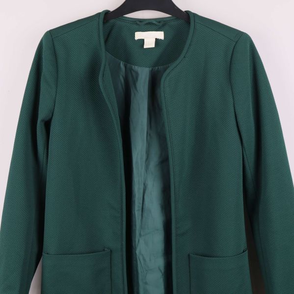 Närbild framtill på grön jacka med två fickor