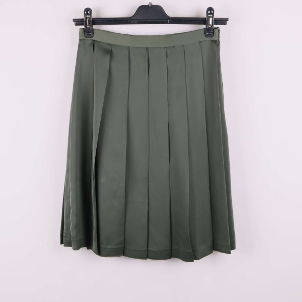 Grön plisserad kjol framifrån på galge