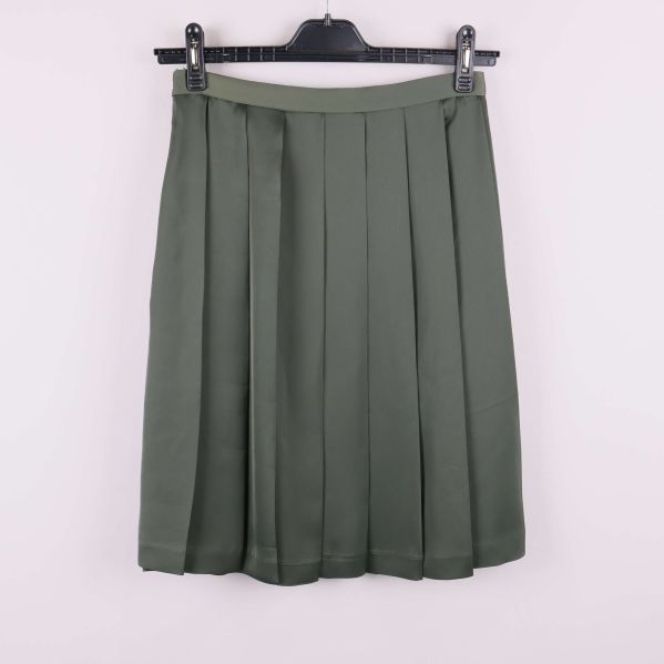 Grön plisserad kjol bakifrån på galge