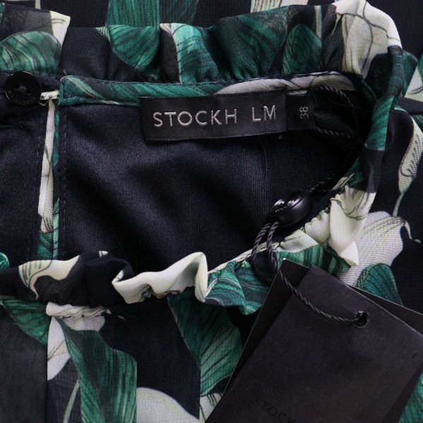 Närbild etikett STOCKH LM i blommig klänning