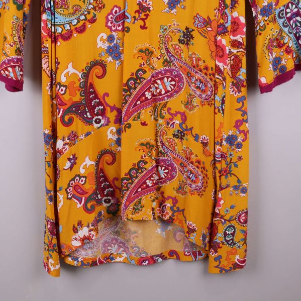 Nederkant på gul klänning med paisleymönster och transparent känsla