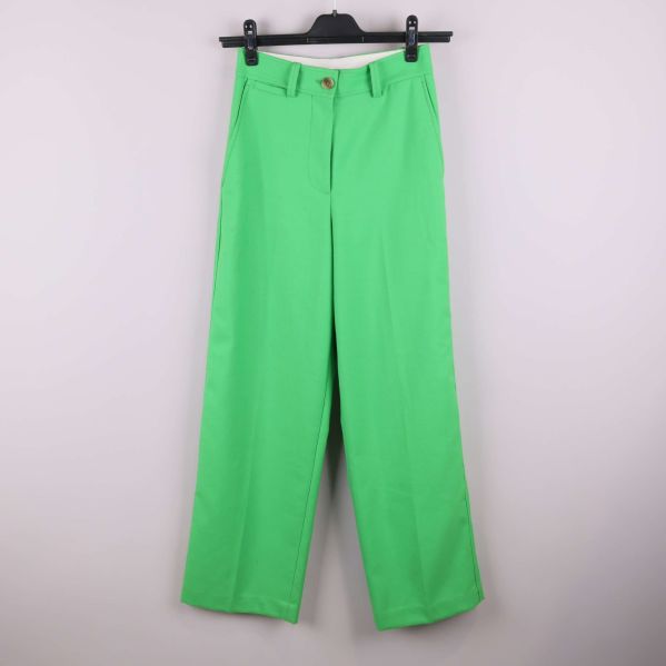 Gröna raka byxor hängande på galge mot ljus bakgrund