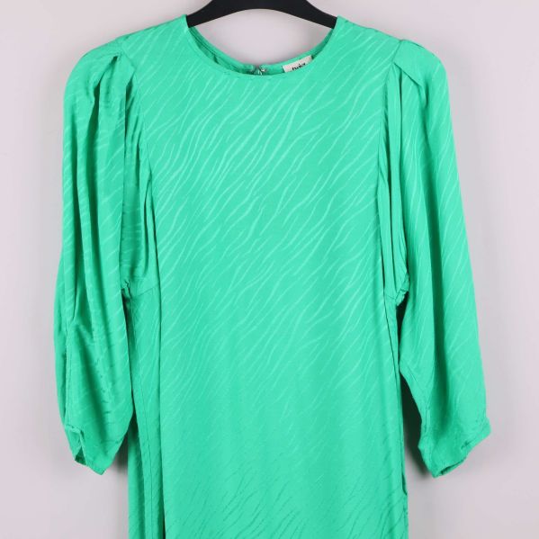 Överkroppsdetalj av grön klänning med struktur