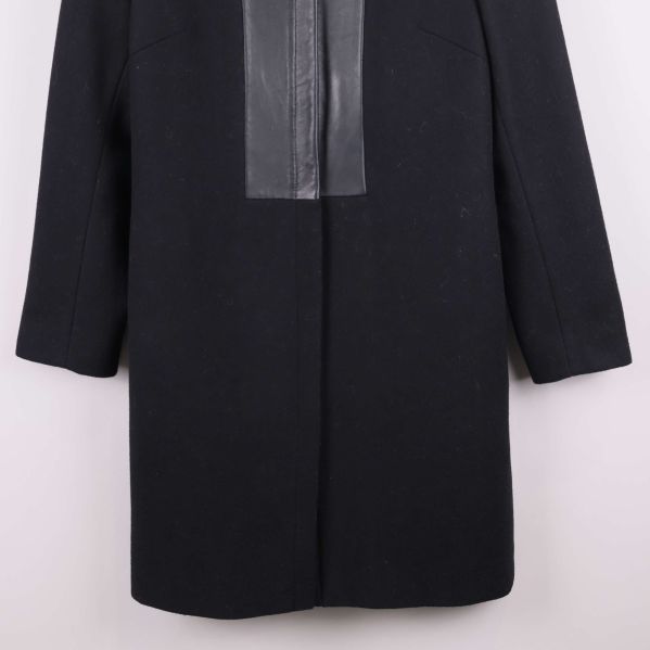 Närbild på nederdelen av svart kappa med skinnimitation