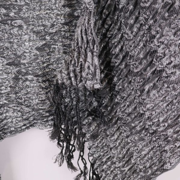 Närbild på gråsvart halsduk med stickat mönster och fina fransar