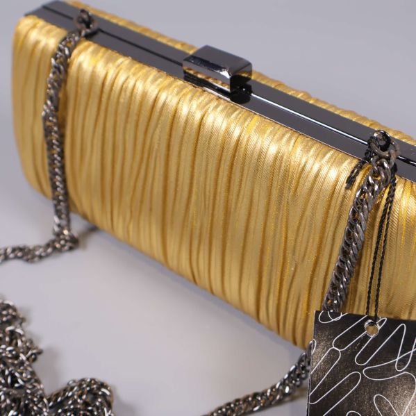 Närbild på guldig rynkad yta och kedjerem på clutch