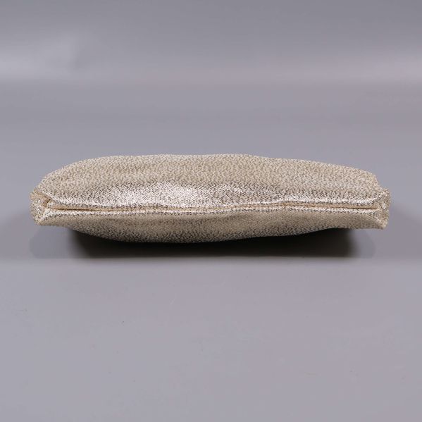 Botten på clutch i guldig färg mot grå bakgrund