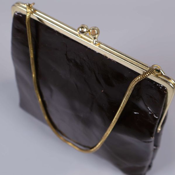 Närbild guldig ram på brun väska