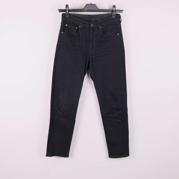 Svarta jeans upphängda på galge mot vit bakgrund