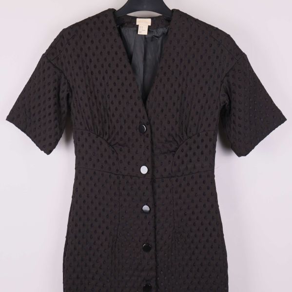 Närbild på kort svart klänning, överdel med knappar