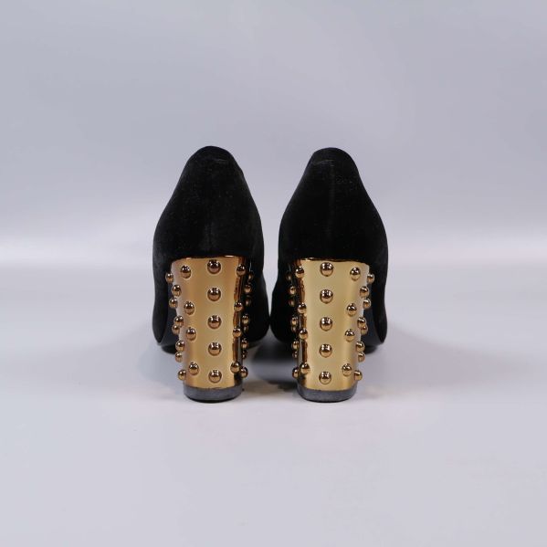 Baksidan av pumps med klack i guld och nitar
