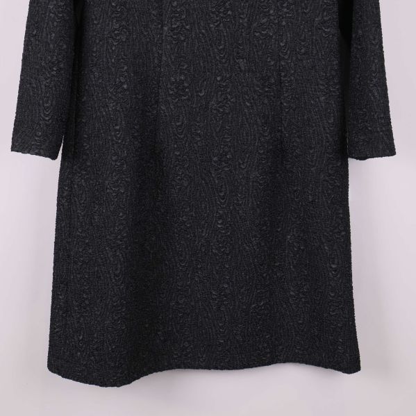 Nederdel av svart strukturerad klänning i närbild