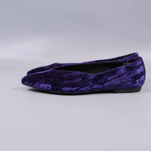 Sida av ballerinasko i lila sammet på grå bakgrund