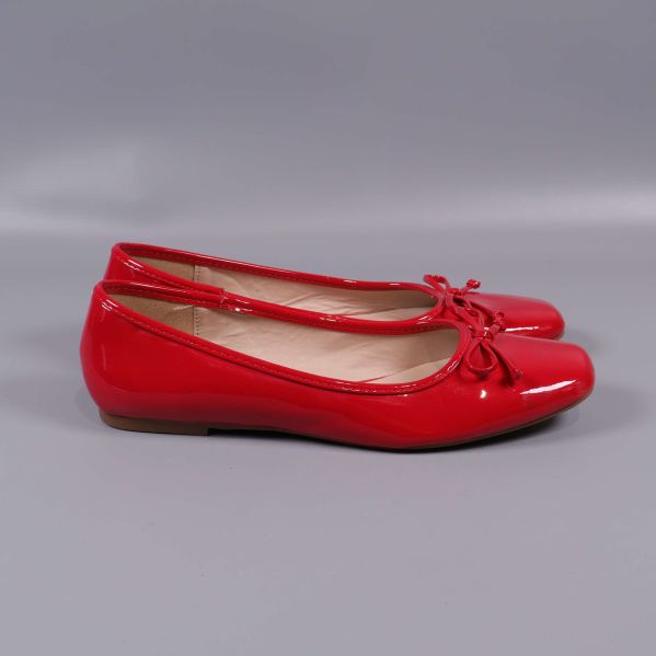 Röda ballerinas sedd från sidan mot grå bakgrund