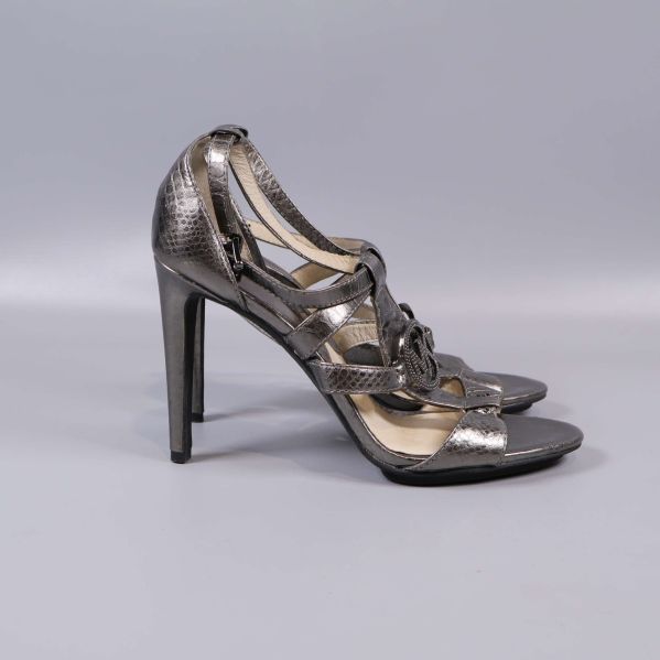 Sidan av sandalerna med struktur och smal klack i fokus