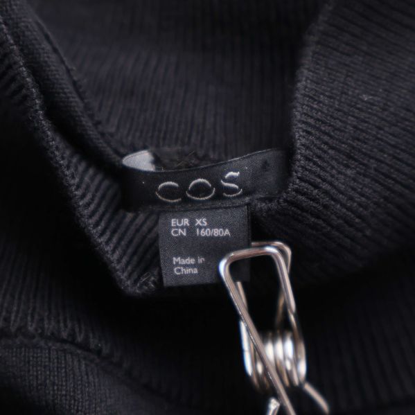 Storlekstag för svart klänning från COS, märkt XS