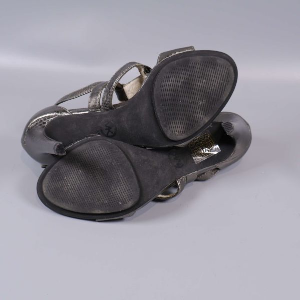 Sandalerna undersida med synliga sulor och slitage