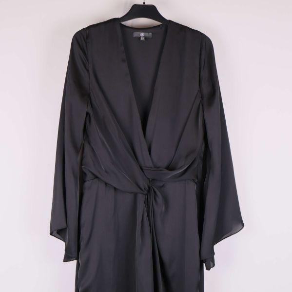 Närbild på v-ringning och knytskärp på svart klänning