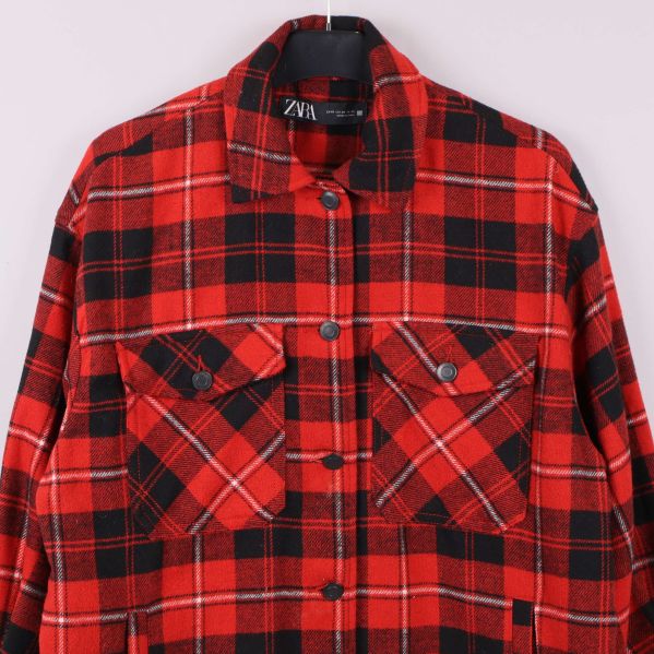 Närbild på bröstfickor och krage av röd-rutig skjortjacka