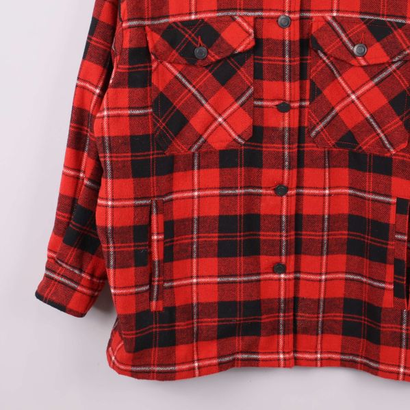 Närbild på undre delen av röd-rutig skjortjacka med fickor