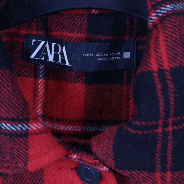 Närbild på ZARA-märkesetikett i kragen på skjortjackan