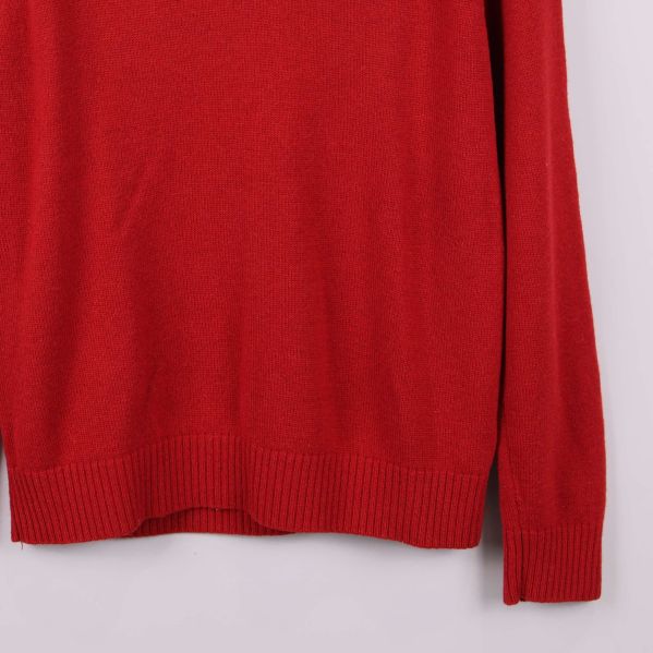 Nedre delen och ärm på röd stickad tröja visas i närbild