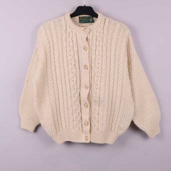 Framsida av grovstickad kofta med kabelmönster och knappar