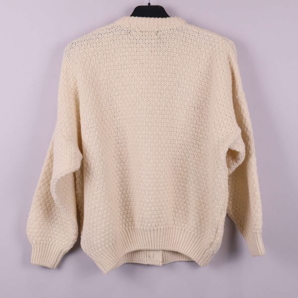 Baksida av ljus grovstickad kofta med ribbad nederkant