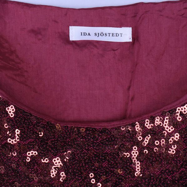 Närbild på Ida Sjöstedt-märkeslapp i klänningens halsringning