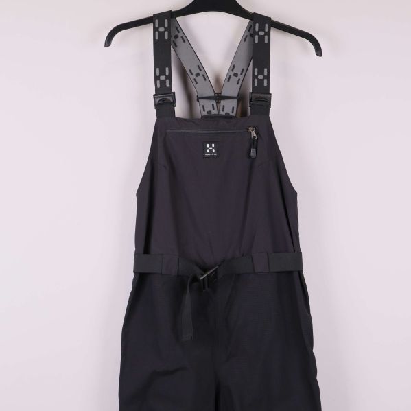 Närbild på midja och framficka på svart hängselbyxa